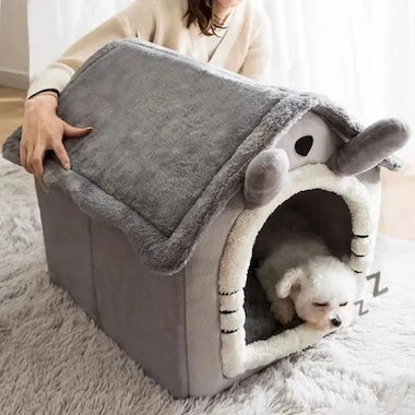 Dog lying in a gray Cozy Pet House Nest with a person holding the top cover.